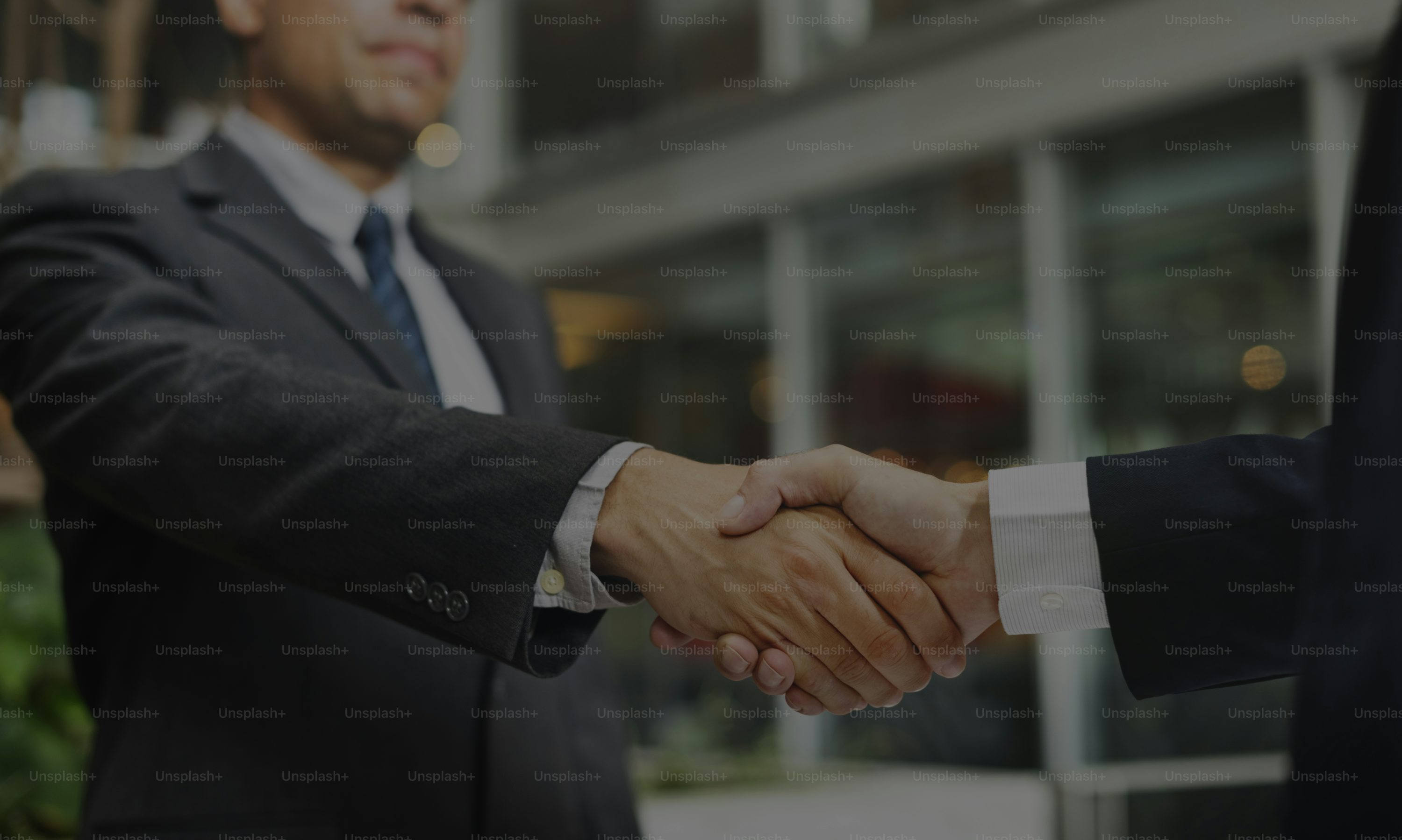 A close-up of two corporate professionals shaking hands in an office setting, symbolizing a successful business agreement and partnership.